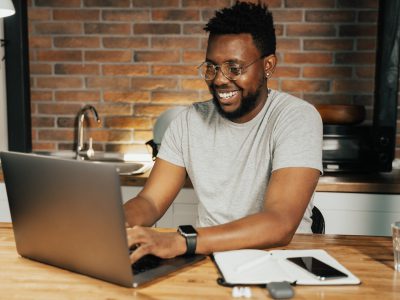 Homem estudando em um computador enquanto sorri